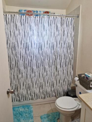 a shower curtain in a bathroom with a toilet at 1-Bed House Sleeps 2 in Secure Community in Old Harbour