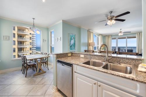 a kitchen with a sink and a dining table at Beach Colony Tower 7A By Pkrm in Pensacola
