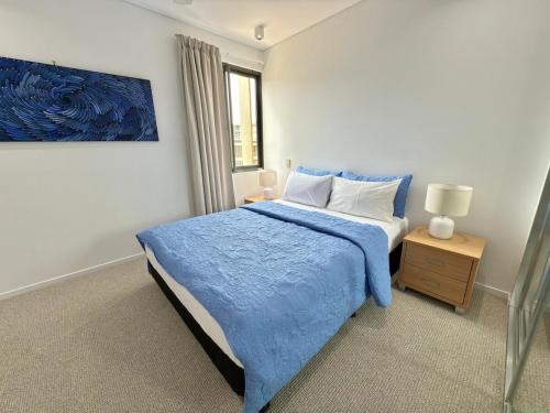 a bedroom with a blue bed with a blue blanket at The Palms at Waterfront in Darwin