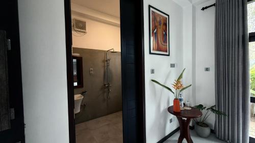 ein Badezimmer mit Dusche, Toilette und einem Tisch in der Unterkunft Priima in Ahangama