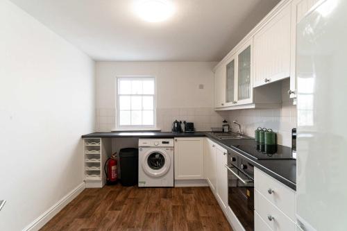 una cucina con mobili bianchi, lavatrice e asciugatrice di Bright 1 Bed Harbour-side Apartment with Balcony a Whitehaven