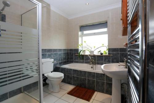 a bathroom with a toilet and a tub and a sink at Bournemouth Holiday Home in Southbourne