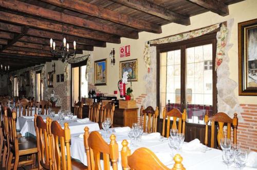 a dining room with white tables and wooden chairs at Posada Restaurante Ducal in Peñaranda de Duero