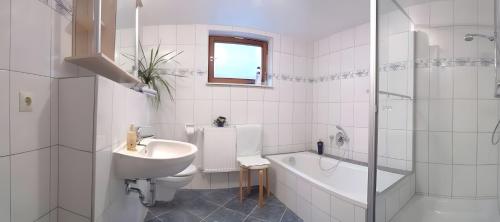 bagno bianco con lavandino, vasca e servizi igienici di Haus Wacholderheide a Onstmettingen