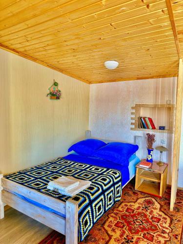 a bedroom with a blue bed with a wooden ceiling at The Secret Garden House in Ijevan