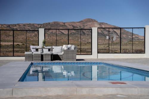 斯普林博克Kénosis Guest Farm Main House的游泳池旁有一张沙发和一张桌子