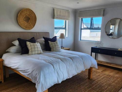 a bedroom with a large bed with pillows and a mirror at White Wicker House in Langebaan
