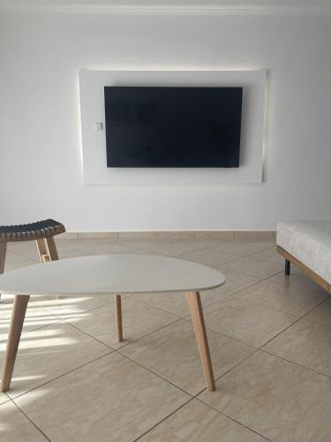 a living room with a table and a tv on a wall at Pnoe Home in Kavála