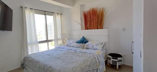 een witte slaapkamer met een bed en een raam bij Chillis Penthouse in Porlamar