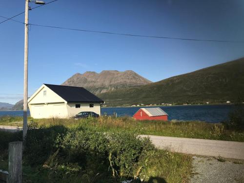 a house and a barn next to a body of water at Paradis in Norway in Nord-Lenangen