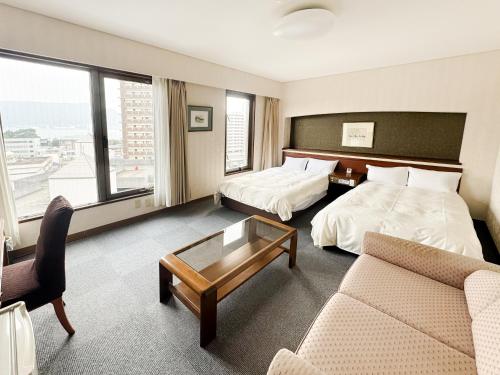 una habitación de hotel con dos camas y un sofá en 下関大坂屋ホテル, en Shimonoseki