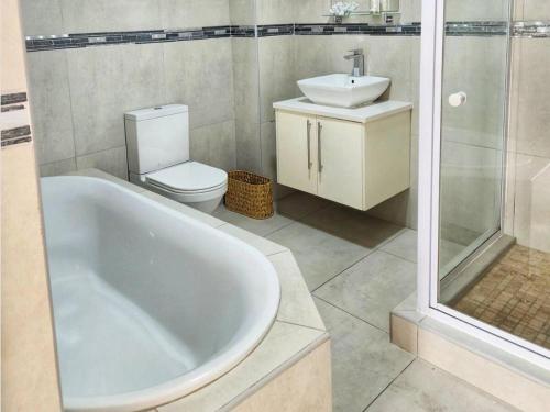 a bathroom with a tub and a toilet and a sink at White Wicker House in Langebaan