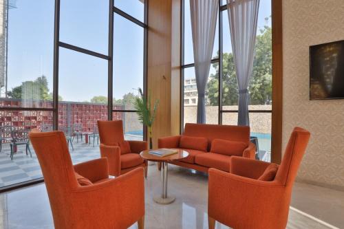 Un vestíbulo con sillas naranjas, un sofá y una mesa. en Empyrean Resort, en Gandhinagar