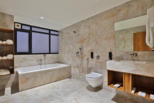 Un baño con bañera, inodoro y lavabo. en Empyrean Resort, en Gandhinagar