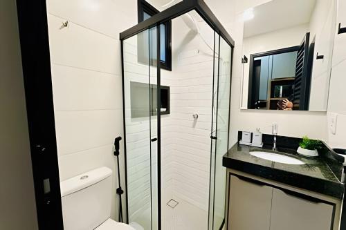 een badkamer met een glazen douche en een wastafel bij Studio Safira | Sofisticação e Harmonia in Uberlândia