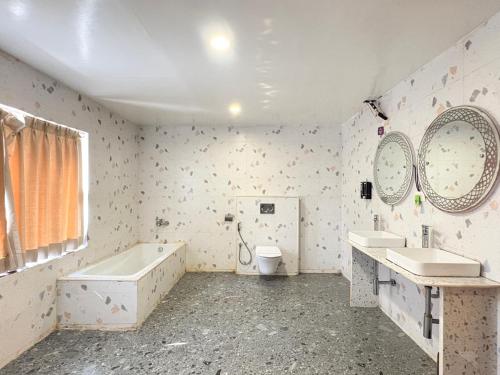 a bathroom with two sinks and a tub and a toilet at Rooftop Sea View Marine Drive Road Duren- Beach-Resort # Jagannath Temple #Fully Air Condition with All Premium Rooms With Attached #Balcony Free Wifi & Lift Facilities- Top Rated Hotel in Puri