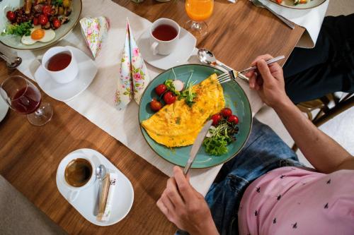 eine Person, die mit einem Teller Essen an einem Tisch sitzt in der Unterkunft PÚŠŤ rekreačné stredisko in Prievidza