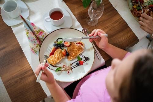 Ein kleines Mädchen, das an einem Tisch mit einem Teller Essen sitzt. in der Unterkunft PÚŠŤ rekreačné stredisko in Prievidza