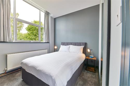 a bedroom with a large bed and two windows at Apartment Stays in Newcastle upon Tyne