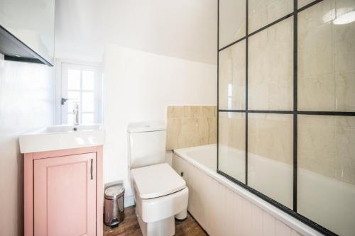 een badkamer met toilet, wastafel en bad bij Pink Cottage in Leiston