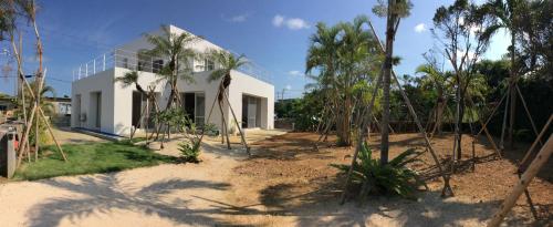 a white house with palm trees in front of it at Seaside House Nirai in Miyako Island