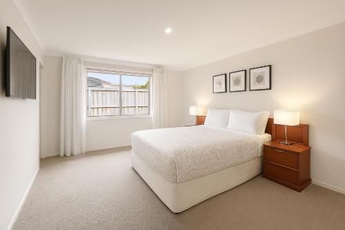 a white bedroom with a bed and a window at Macs Manor in Dunsborough