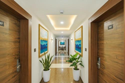 a hallway with two potted plants and wooden doors at Via Heera Holiday Inn - Nr Eden Garden Stadium in Kolkata