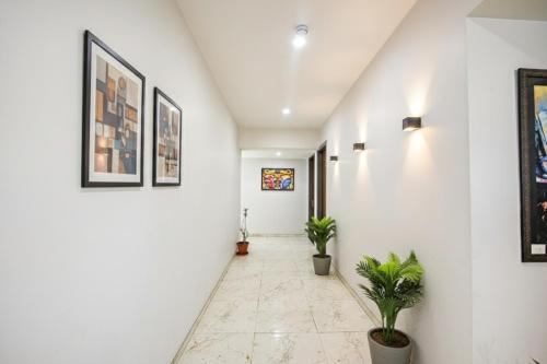 um corredor com paredes brancas e vasos de plantas em FabHotel Gazelle Inn em Gurgaon