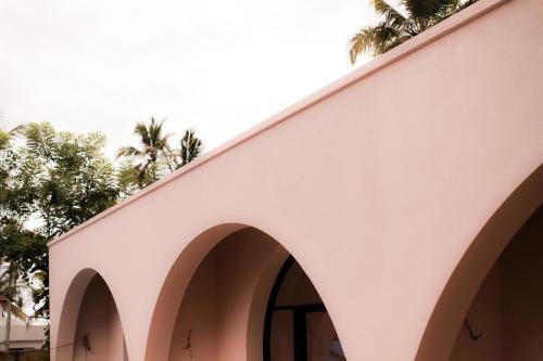 a white building with arches and palm trees in the background at Together Boutique Villa in Ahangama
