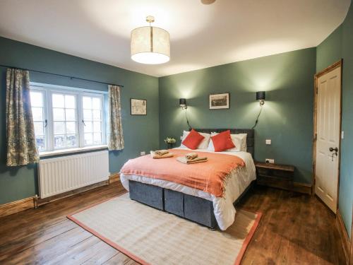 a bedroom with green walls and a bed with red pillows at Highfields Farm in Church Stretton