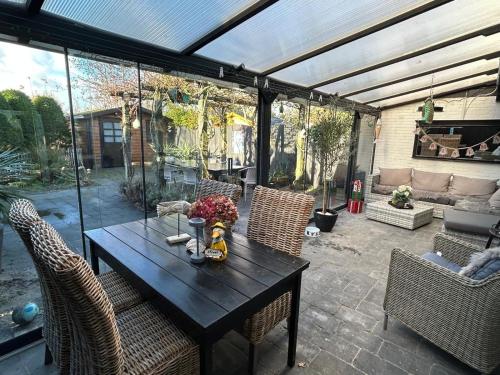 eine Terrasse mit einem Holztisch mit Stühlen in der Unterkunft Lichtdurchflutetes Traumhaus 400 Meter zum Strandaufgang, uneinsehbarer Garten mit Terrassenüberdachung, hundefreundlich in Sint Maartenszee