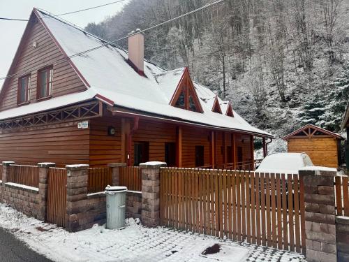a wooden house with a fence in the snow at Chata Bella in Mýto pod Ďumbierom