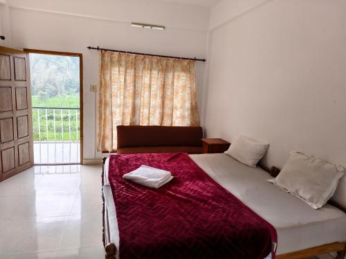 Un dormitorio con una cama grande y una ventana. en Wild Forest Inn Thekkady, en Thekkady