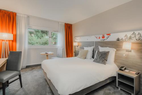 a hotel room with a large bed and a chair at Mercure Annecy Sud in Annecy