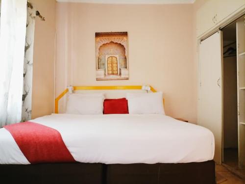 una camera da letto con un grande letto bianco con un cuscino rosso di Chiloto Guest House a Kasane