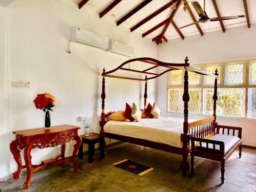 a bedroom with a canopy bed and a table at The Colony Hotel in Habaraduwa