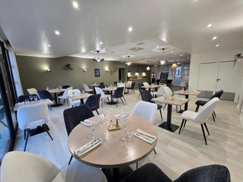 una sala da pranzo con tavoli e sedie bianche di Hôtel Restaurant Les Fontaines a Lanvollon