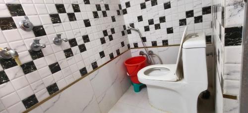 ein Badezimmer mit einem WC und einem roten Eimer in der Unterkunft Sri Narayan Home Stay in Ayodhya