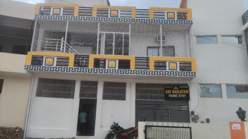 ein weißes Gebäude mit einem gelben Balkon darauf in der Unterkunft Sri Narayan Home Stay in Ayodhya