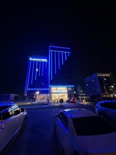 a blue building with cars parked in a parking lot at night at Saray Deluxe Hotel Apartments in Abu Dhabi