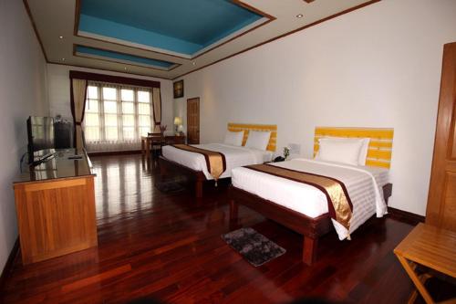 una camera d'albergo con due letti e una televisione di Myanmar Life Hotel a Yangon