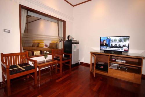 a living room with a television and a table and chairs at Myanmar Life Hotel in Yangon