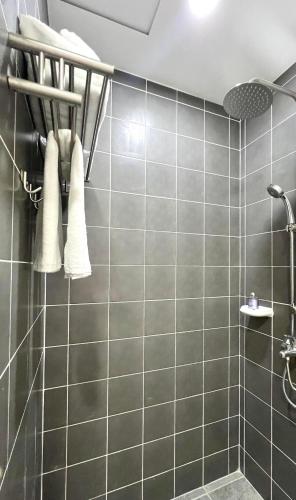 une salle de bains avec un mur carrelé gris et des serviettes dans l'établissement AMANI GRAND CITYGATE STUDIO by ADORE IT, à Davao