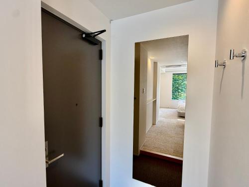 una puerta que da a un pasillo con un espejo en Vive Boutique Hotel - Echoland, en Hakuba