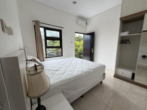 a white bedroom with a bed and a window at Pandan de Bali in Ungasan