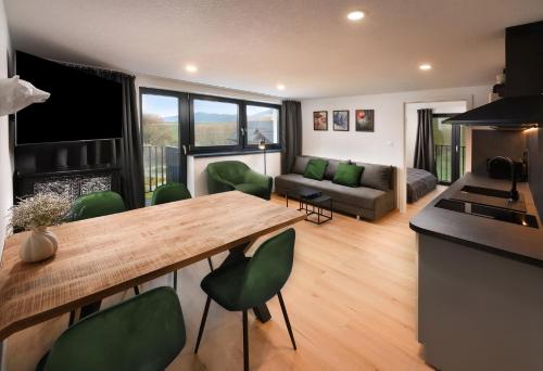 eine Küche und ein Wohnzimmer mit einem Holztisch und grünen Stühlen in der Unterkunft Sky-House Jasná Apartments in Pavčina Lehota