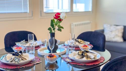 a table with plates and glasses and a rose in a vase at Bon Bon Suite by Ca-sa Check in Sottomarina