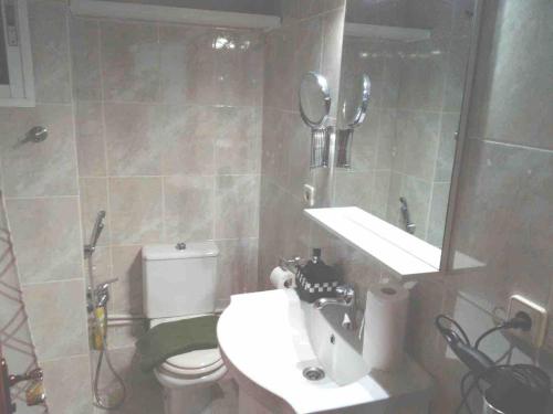 un bagno con lavandino, WC e specchio di Beach apartment a Valencia