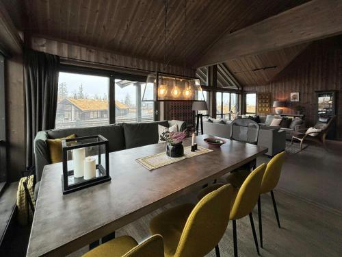 a living room with a large wooden table and yellow chairs at Modern Cabin With Views Of Skeikampen in Svingvoll