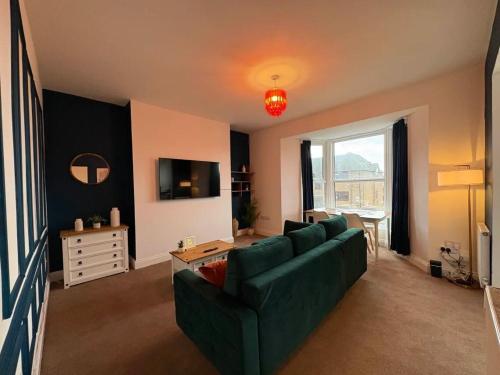 a living room with a green couch and a television at Spacious 2 Bed Apartment in Central Margate in Margate